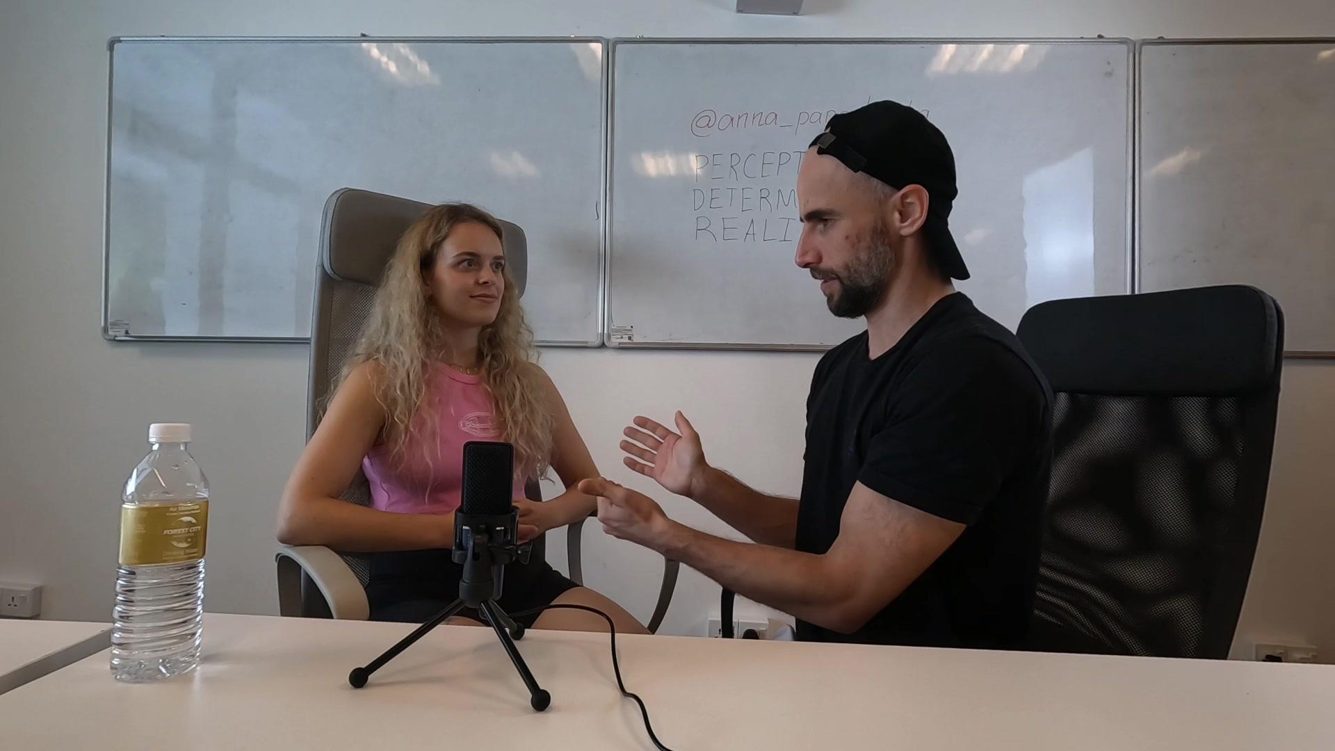 Konrad gesturing mid-conversation with Anna Sokol at Network School