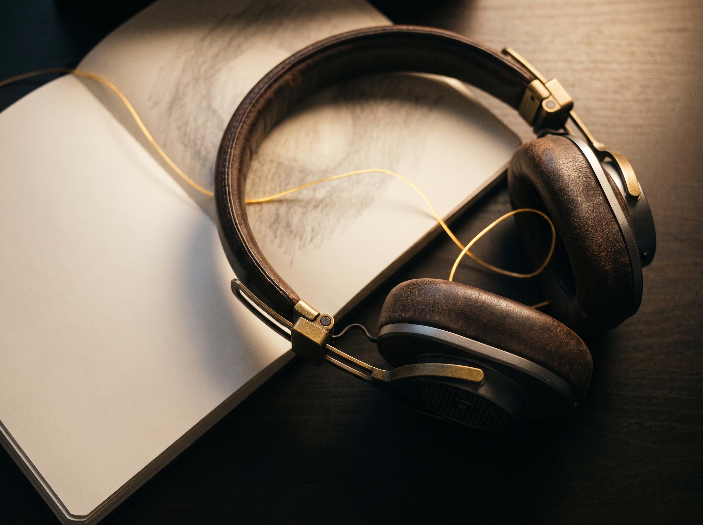 A pair of headphones resting on an open notebook in lamplight