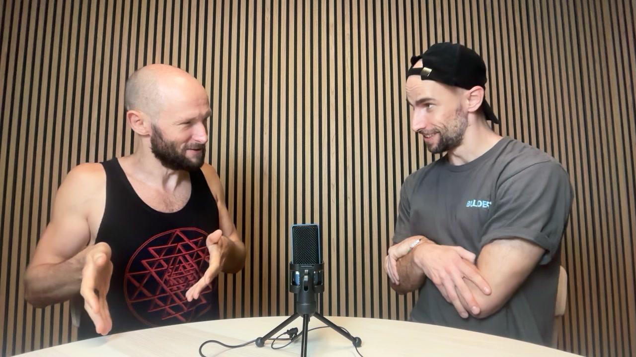 Chris Smith (UV Lightman) in conversation at Network School, gesturing as he explains an idea across the podcast microphone
